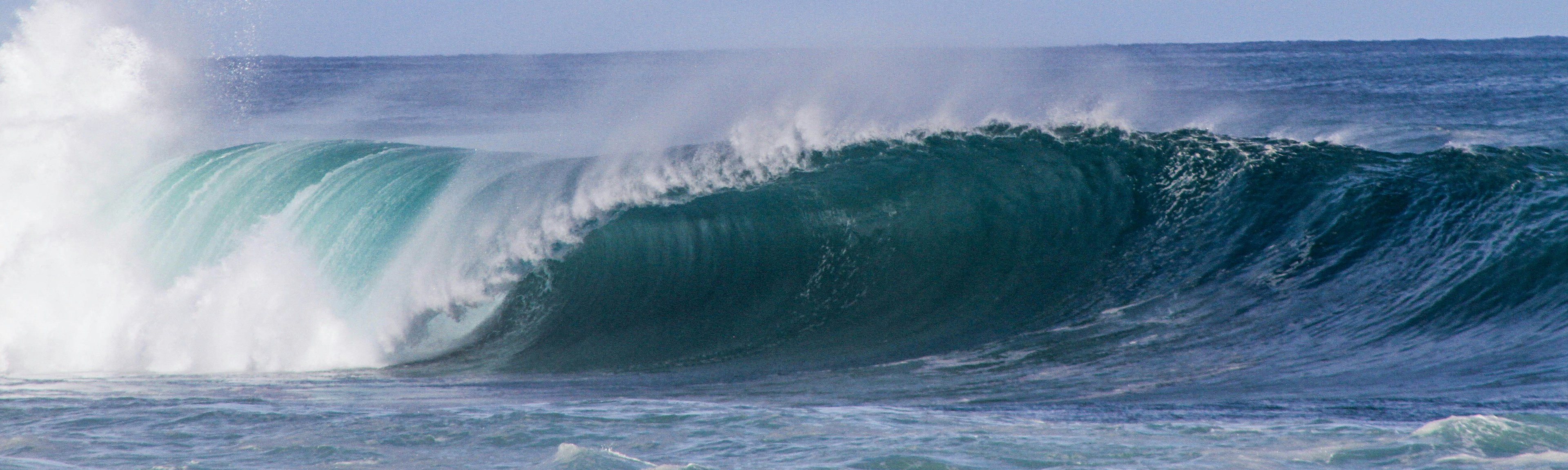 {generated} Powerful turquoise wave curling beneath a bright sky, capturing ocean energy and the dynamic Surfrider spirit