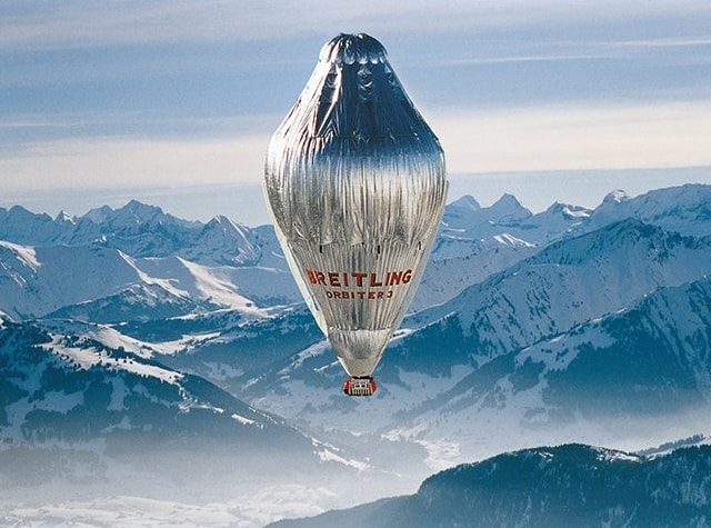 {generated} A silver Breitling balloon drifts over snowy mountain peaks, reflecting the innovative vision of the Solar Impulse Foundation.