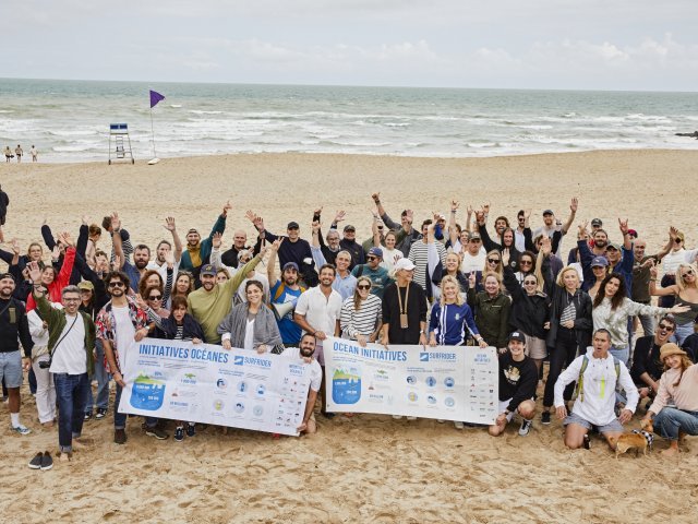 {generated} Volunteers gathered on a sandy beach holding ocean-initiative banners, united in a shared mission to protect marine health