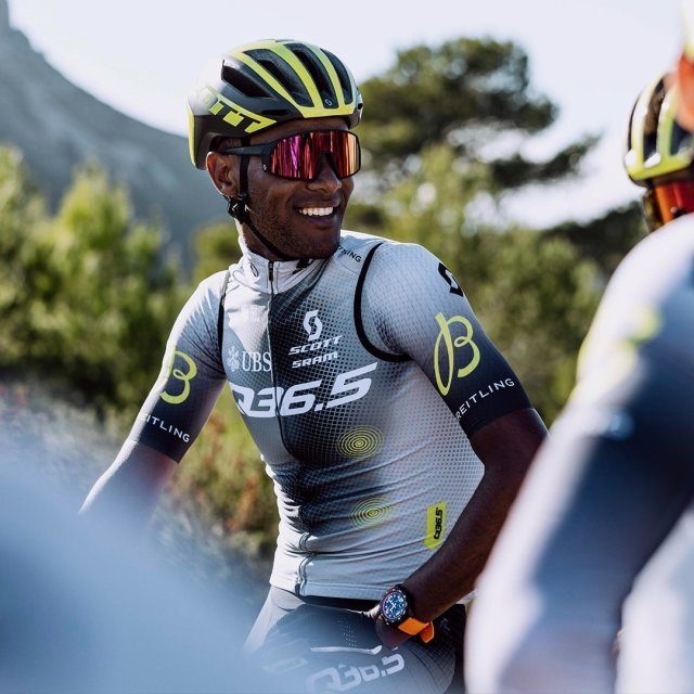 {generated} 身穿Q36.5騎行服的車手在戶外騎行，在明亮景致中襯托腕間的Breitling腕錶。