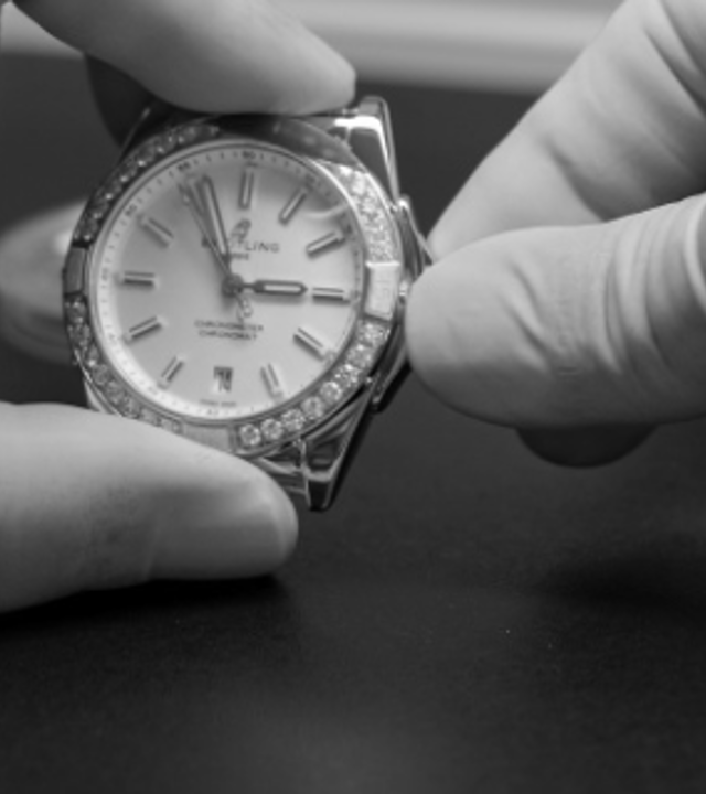 {generated} Technician’s gloved hands carefully inspecting a Breitling watch during a precision service procedure.