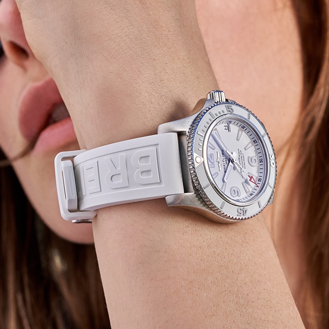 {generated} 女性手腕佩戴白色錶盤與壓紋白色錶帶的Breitling Superocean，以精緻特寫呈現。