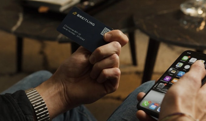 {generated} Hand holding a Breitling warranty card beside a smartphone, highlighting secure registration of a Chronomat B01 42.