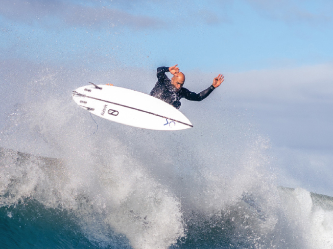 {generated} Surfer launching above a breaking wave, capturing dynamic motion to highlight Breitling water resistance capability.