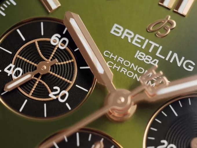 {generated} Close-up of a green Breitling chronograph dial highlighting rose-gold hands, detailed subdials, and refined finishing
