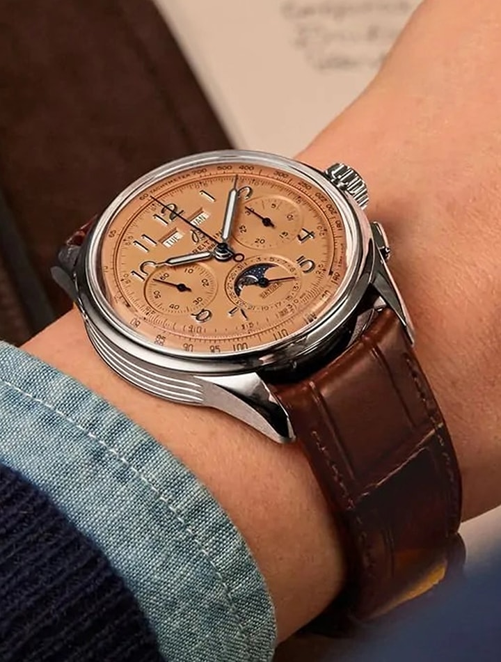 {generated} Orologio Breitling con quadrante rame, fase lunare e cinturino in pelle marrone al polso con dettagli ricercati