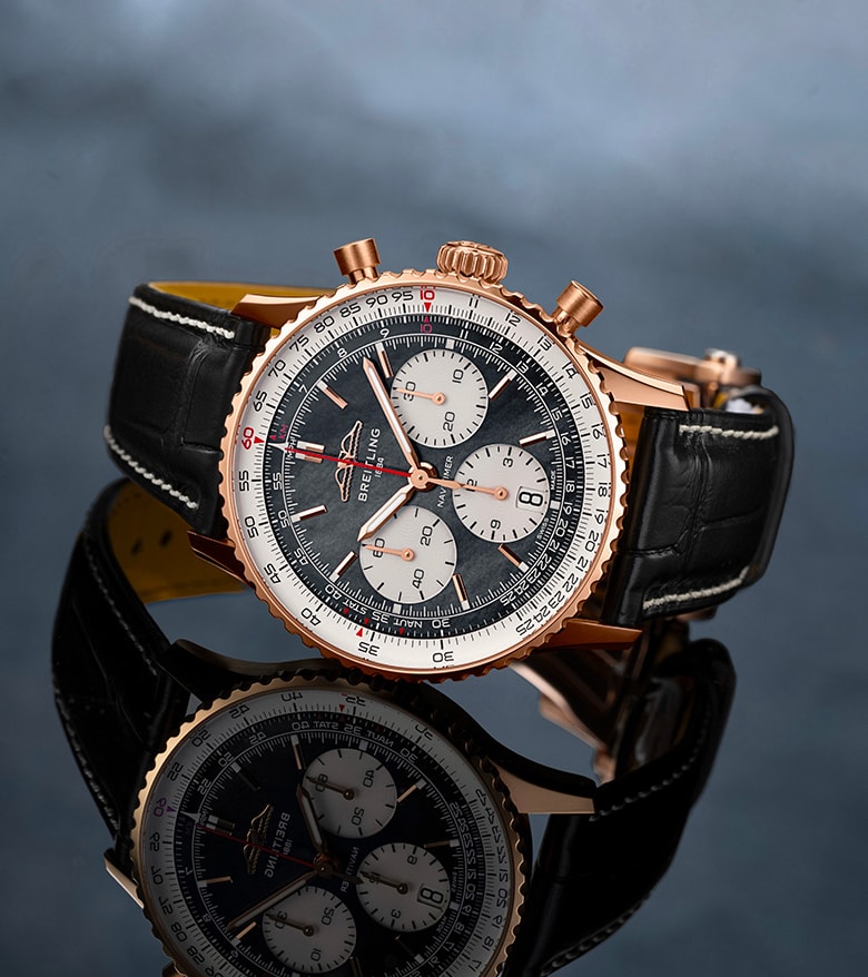 {generated} ブレイトリングのナビタイマーが黒いレザーストラップとともに暗い反射面に置かれ、細部が際立つ構図