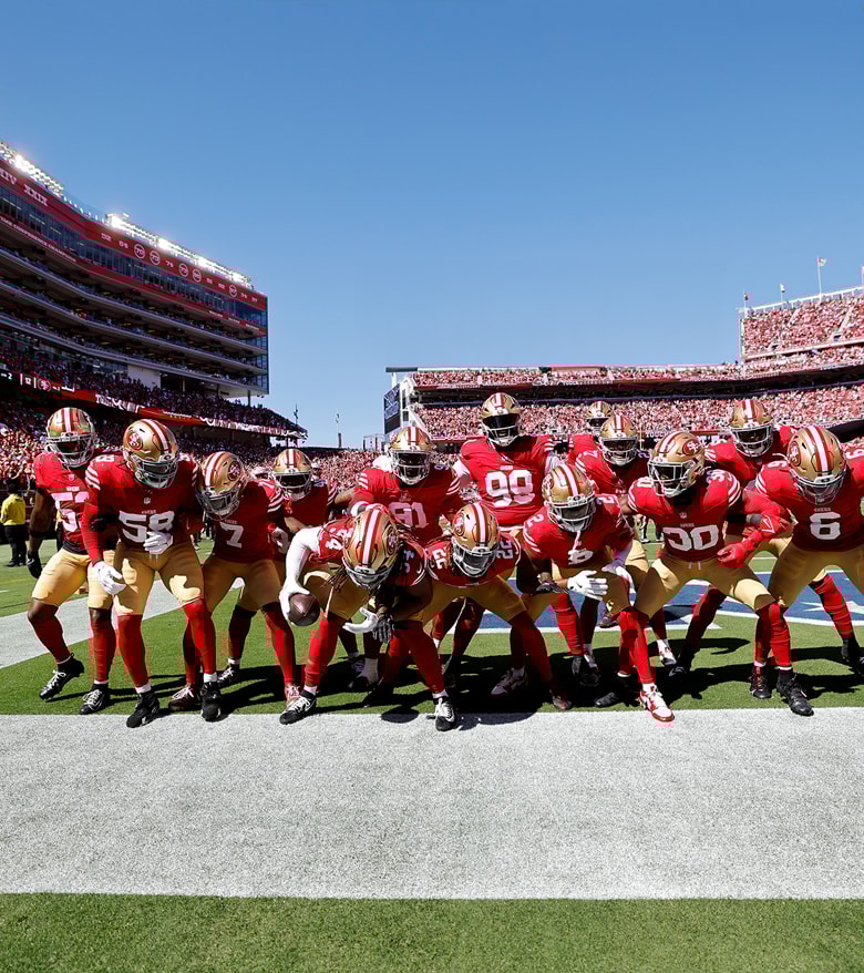 {generated} San Francisco 49ers players unite in red and gold on the field, expressing team spirit within Breitling’s NFL link
