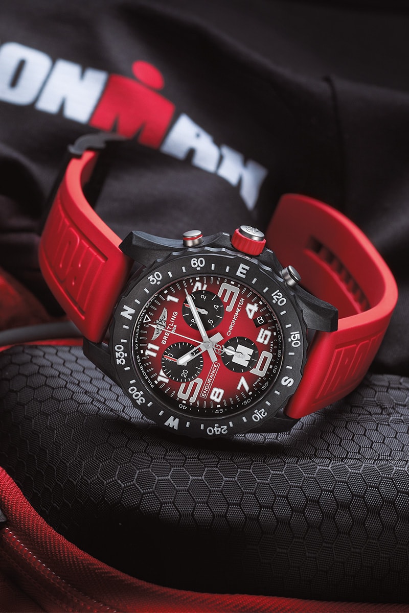 {generated} Montre Breitling Endurance Pro Ironman à cadran et bracelet rouges posée sur du matériel sportif, soulignant son design performant