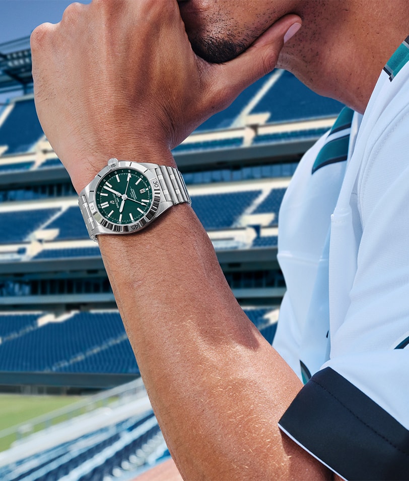 {generated} A man in a team jersey wears a green‑dial Breitling Chronomat against a bright stadium backdrop reflecting strong NFL team spirit.