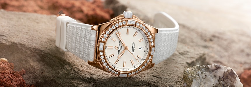 {generated} Breitling Origins watch with white strap and diamond-set bezel resting on rugged stone amid soft mist.