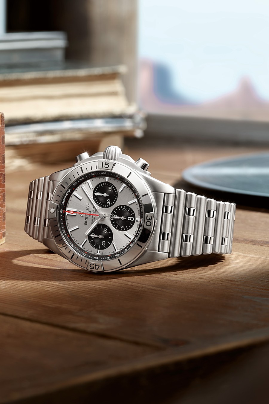 {generated} Breitling Chronomat sobre una superficie de madera, destacando su caja de acero, brazalete metálico y esfera plateada.