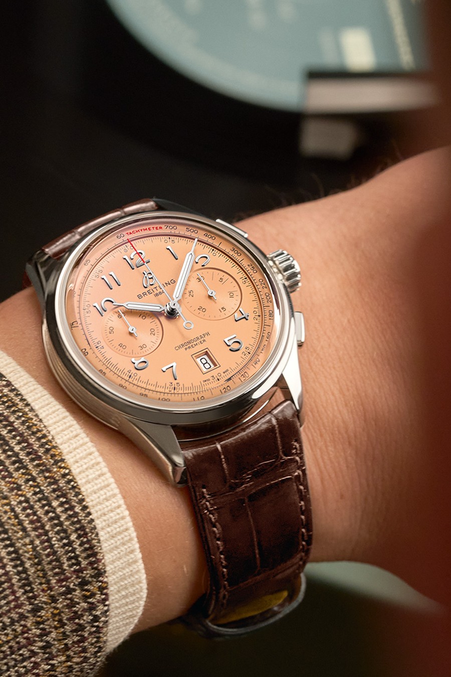 {generated} Cronógrafo Breitling con esfera salmón y correa de cuero marrón en la muñeca, resaltando sus detalles refinados