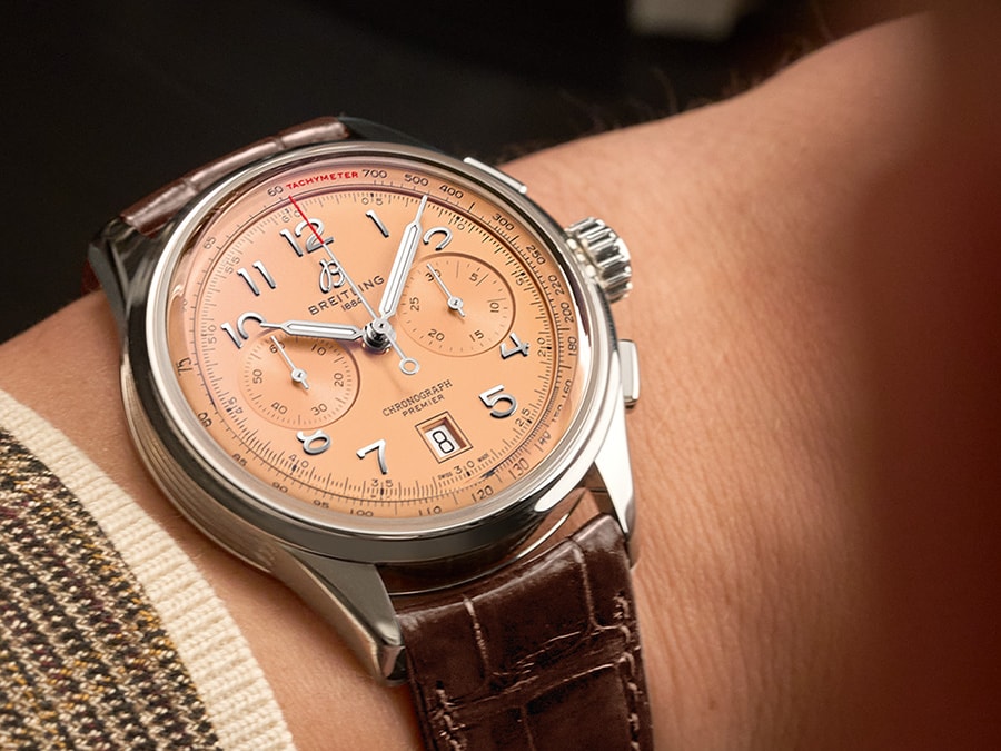 {generated} Cronógrafo Breitling con esfera salmón y correa de cuero marrón en la muñeca, resaltando sus detalles refinados
