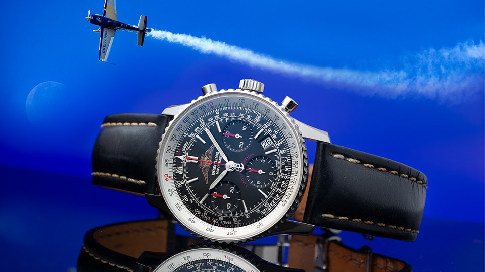 {generated} 鮮やかな空を背景にブレイトリング ナビタイマーと曲技飛行機の煙跡が映え、航空への伝統を強調する構図