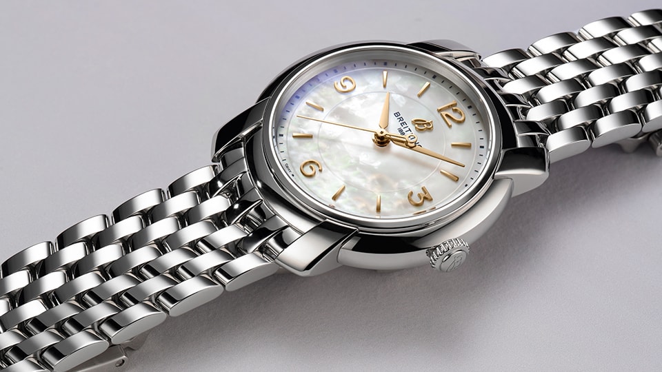{generated} マザーオブパール文字盤と磨かれたメタルブレスのBreitling Lady Premierを上品なクローズアップで示す。