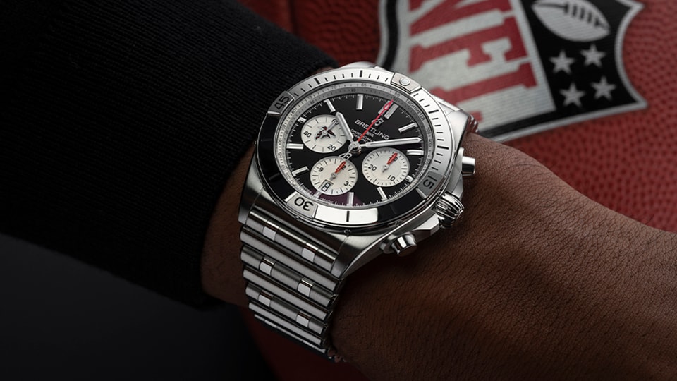 {generated} Breitling Chronomat on a wrist shown against an Atlanta Falcons NFL football, highlighting its polished steel design