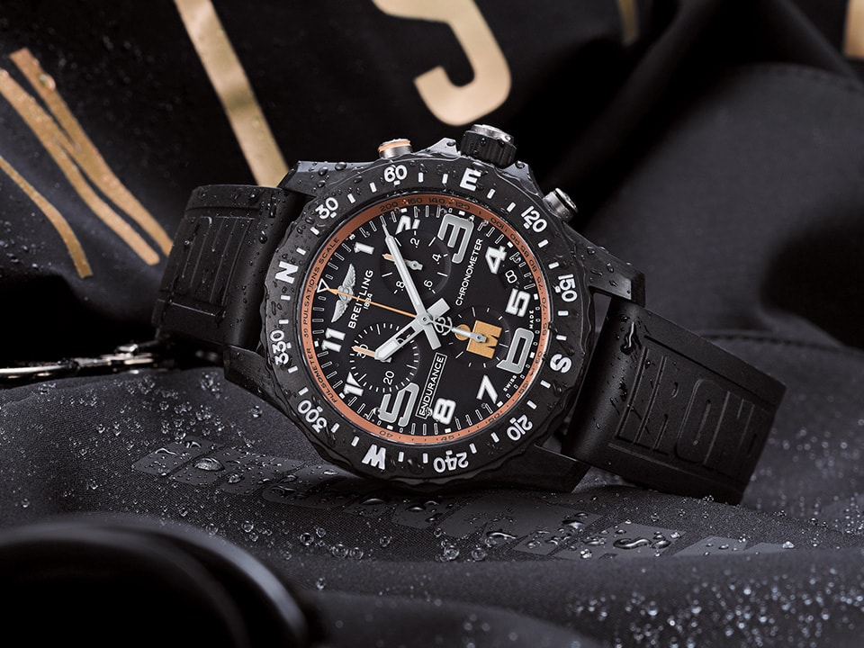 {generated} Montre Breitling Endurance Pro Ironman au bracelet noir en caoutchouc posée sur un équipement sportif mouillé