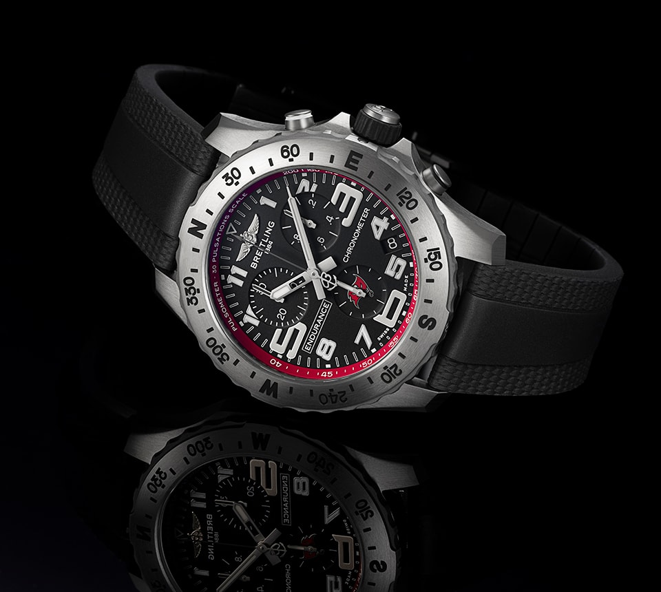 {generated} Breitling Endurance Pro watch with black dial, red Buccaneers accents and rubber strap set on a reflective background