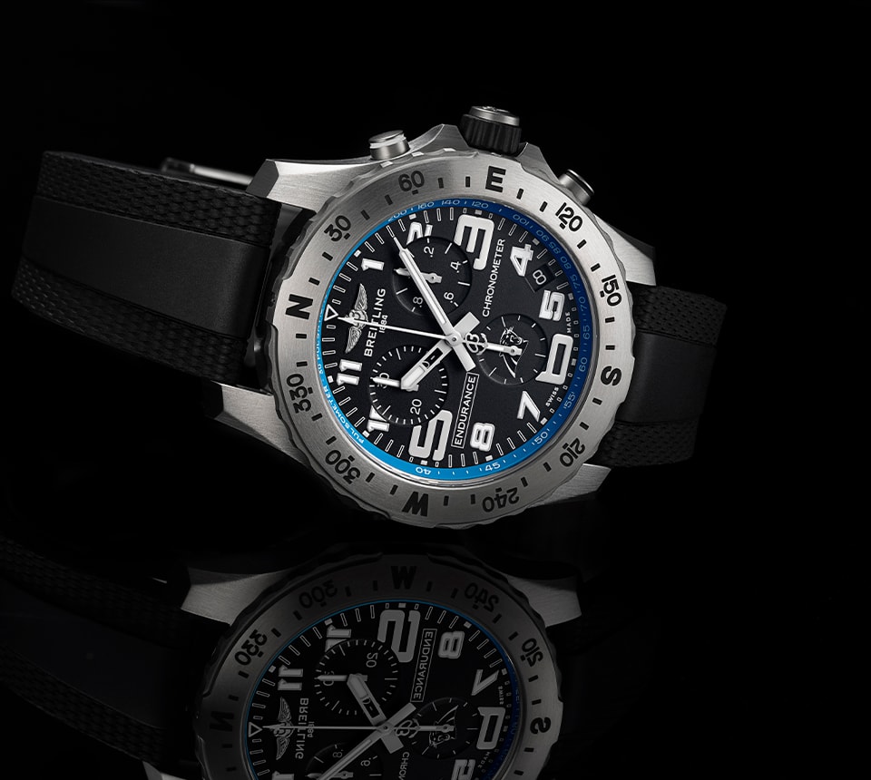 {generated} Breitling Endurance Pro腕錶以黑色錶盤與藍色細節呈現，置於深色反射表面之上。