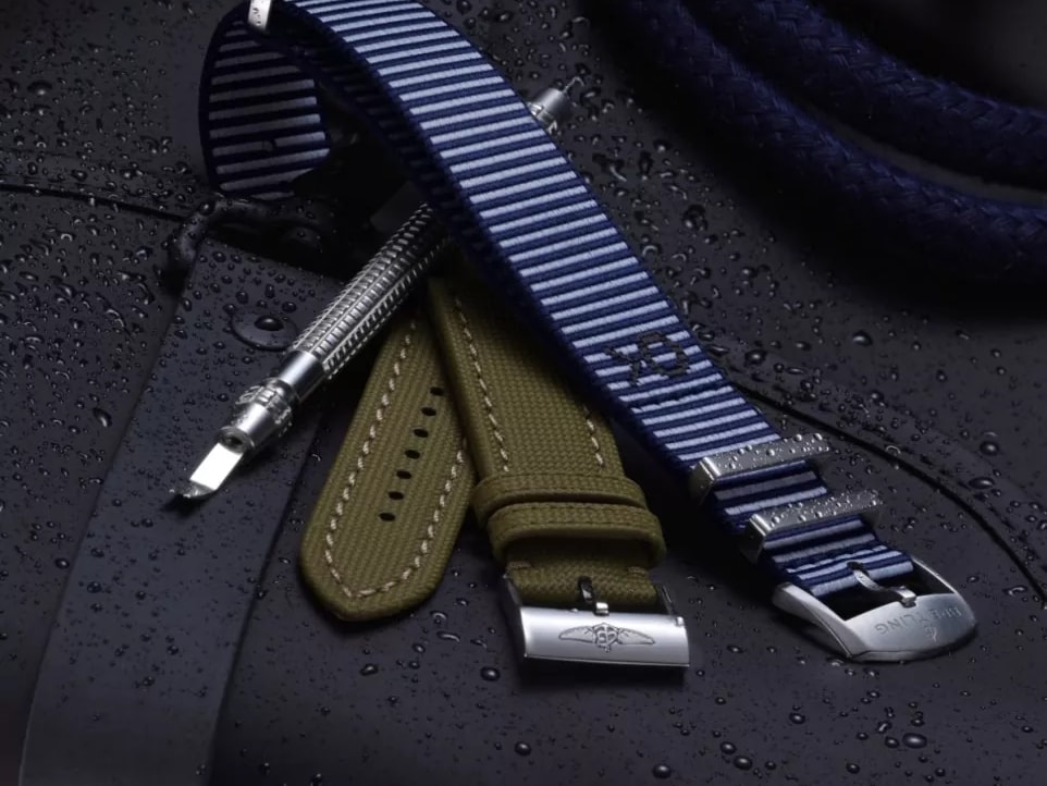 {generated} Полосатые и хаки ремешки Breitling с фирменными пряжками на влажном тёмном снаряжении рядом с металлическим инструментом для замены