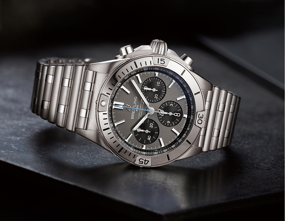 {generated} グレーの文字盤とリンクブレスレットを備えたステンレス製Breitling Chronomatクロノグラフが暗い面に置かれている