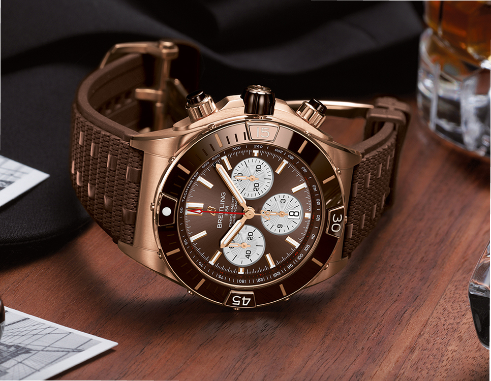 {generated} 木製面に置かれたBreitling Chronomatがブロンズケースとブラウン文字盤、質感あるブラウンストラップを際立てる。