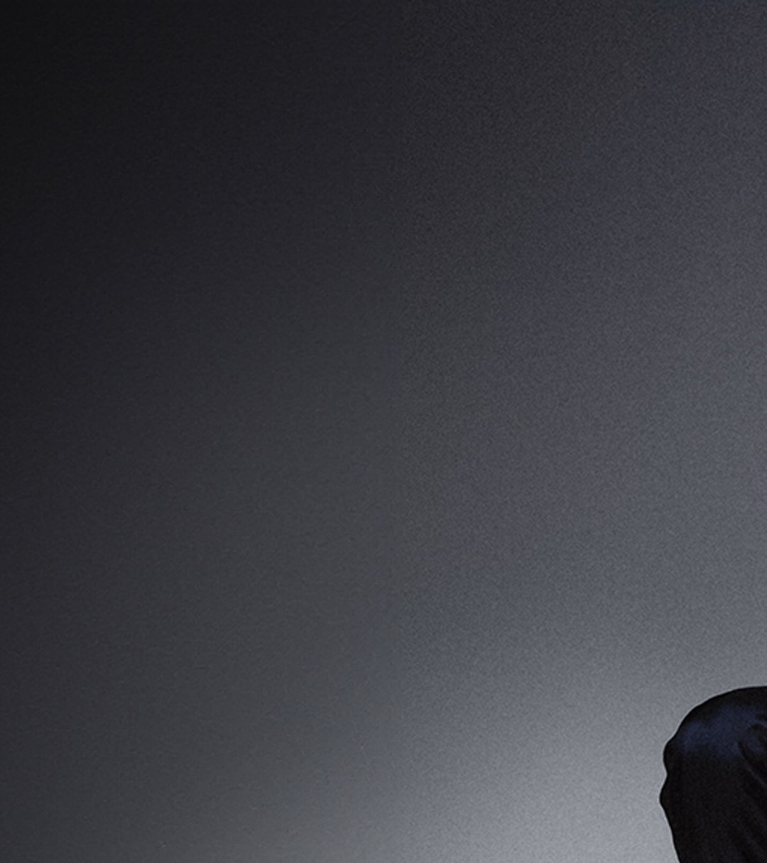 {generated} A seated male ambassador in sportswear highlights a gold Breitling watch against a dark backdrop with a composed posture.