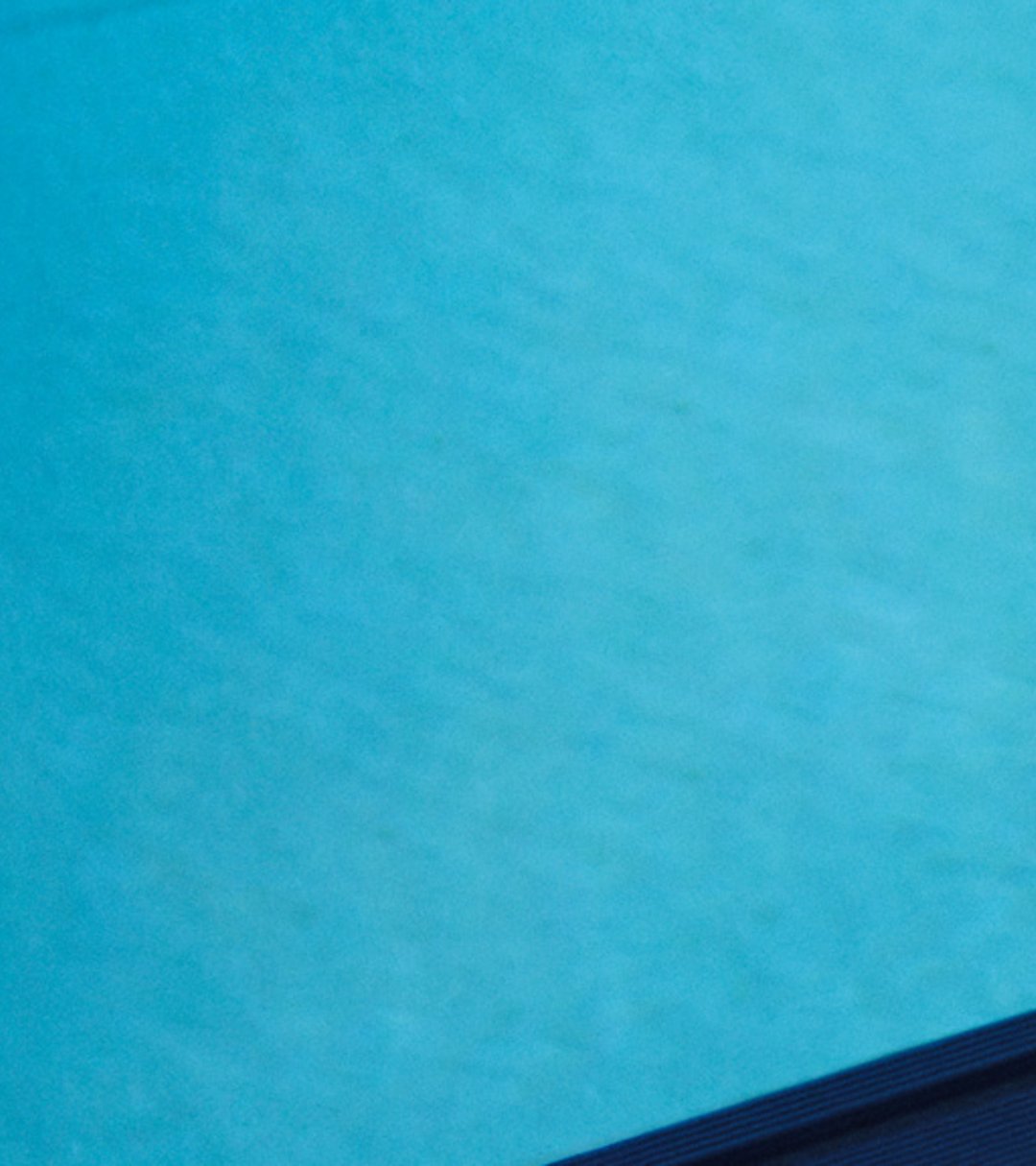 {generated} Swimmer in a wetsuit rests by the pool wearing a Breitling watch with a vivid strap against the bright blue water