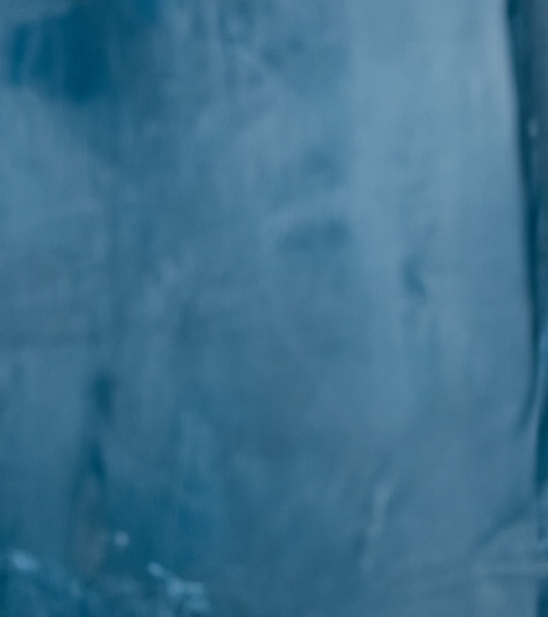 {generated} A woman in a dark jacket poses with hands raised, showcasing a Breitling watch against a softly lit studio backdrop.