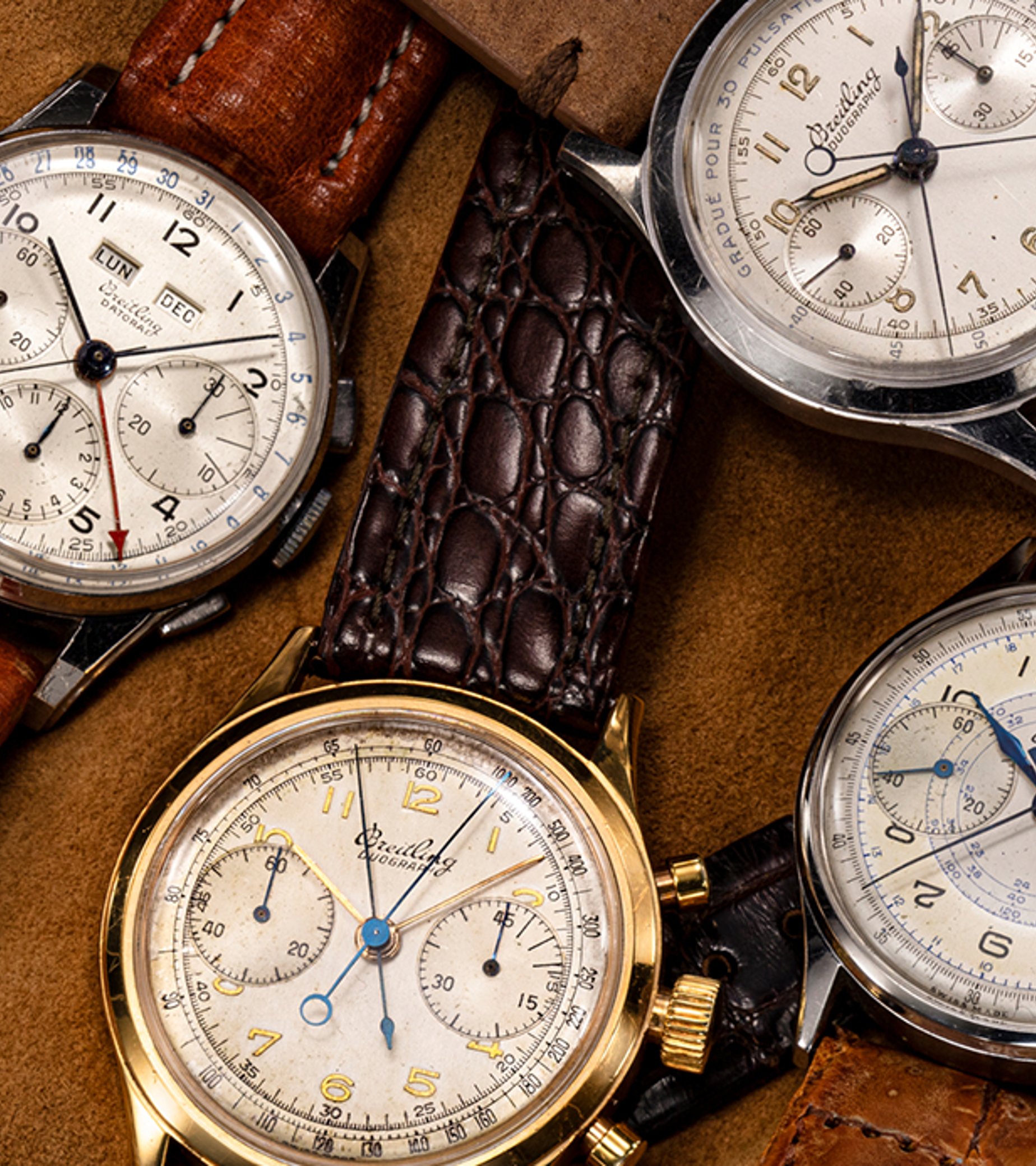{generated} Vintage Breitling Premier chronographs arranged on soft tan fabric, displaying varied dials and leather straps