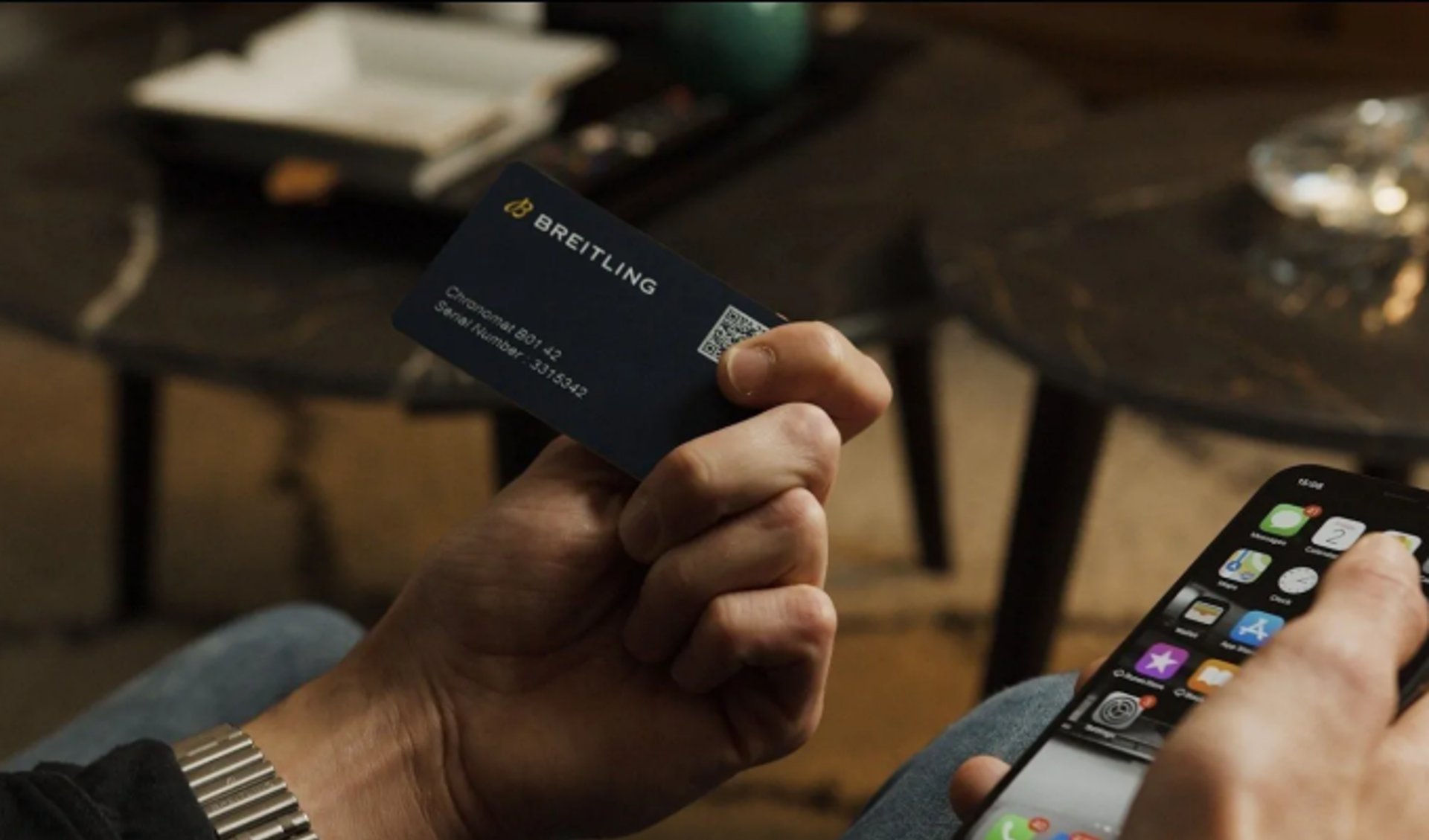 {generated} Hand holding a Breitling warranty card beside a smartphone, emphasising secure registration of a Chronomat B01 42.