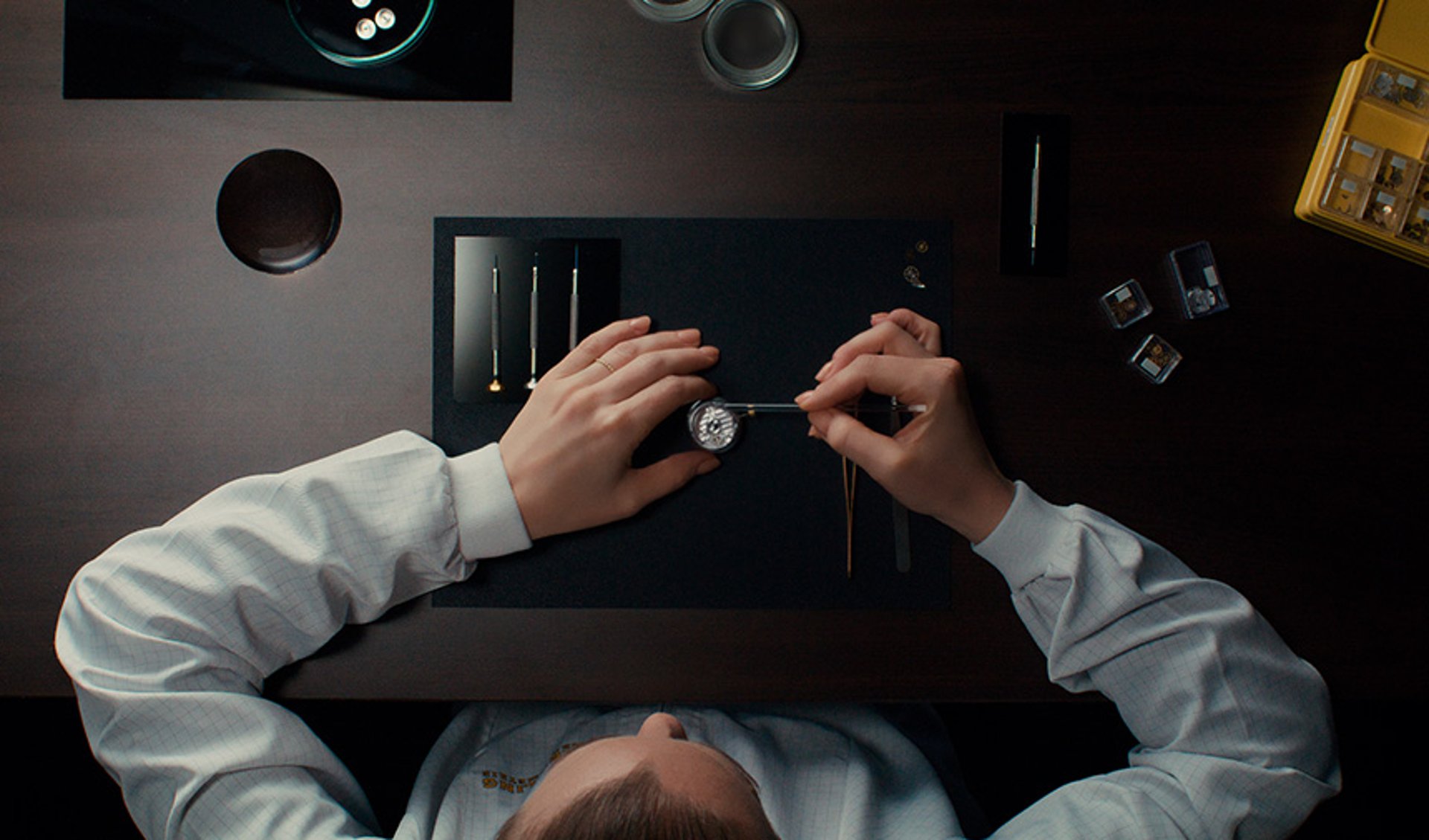 {generated} Watchmaker delicately services a Breitling movement on a dark workspace with precision tools arranged for meticulous care