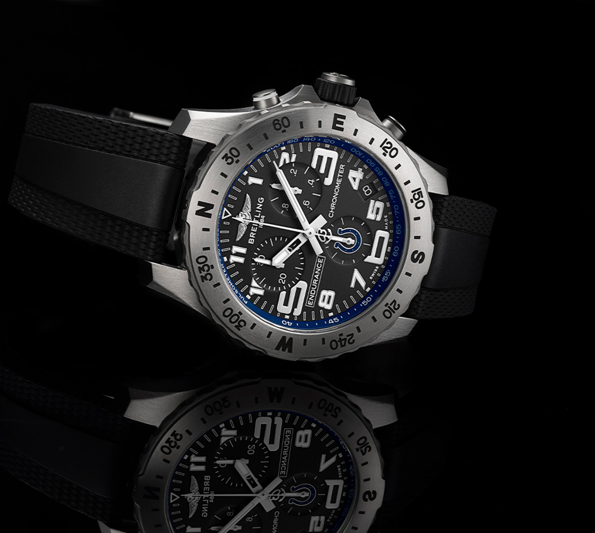 {generated} Breitling Endurance Pro watch with black strap and blue Colts detailing displayed on a reflective black surface