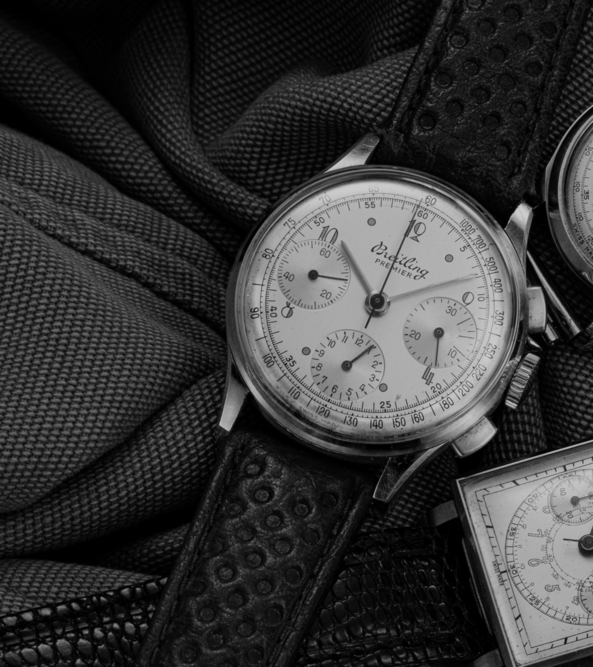 {generated} Vintage Breitling Premier chronographs arranged on textured fabric, highlighting classic dials, cases, and leather straps