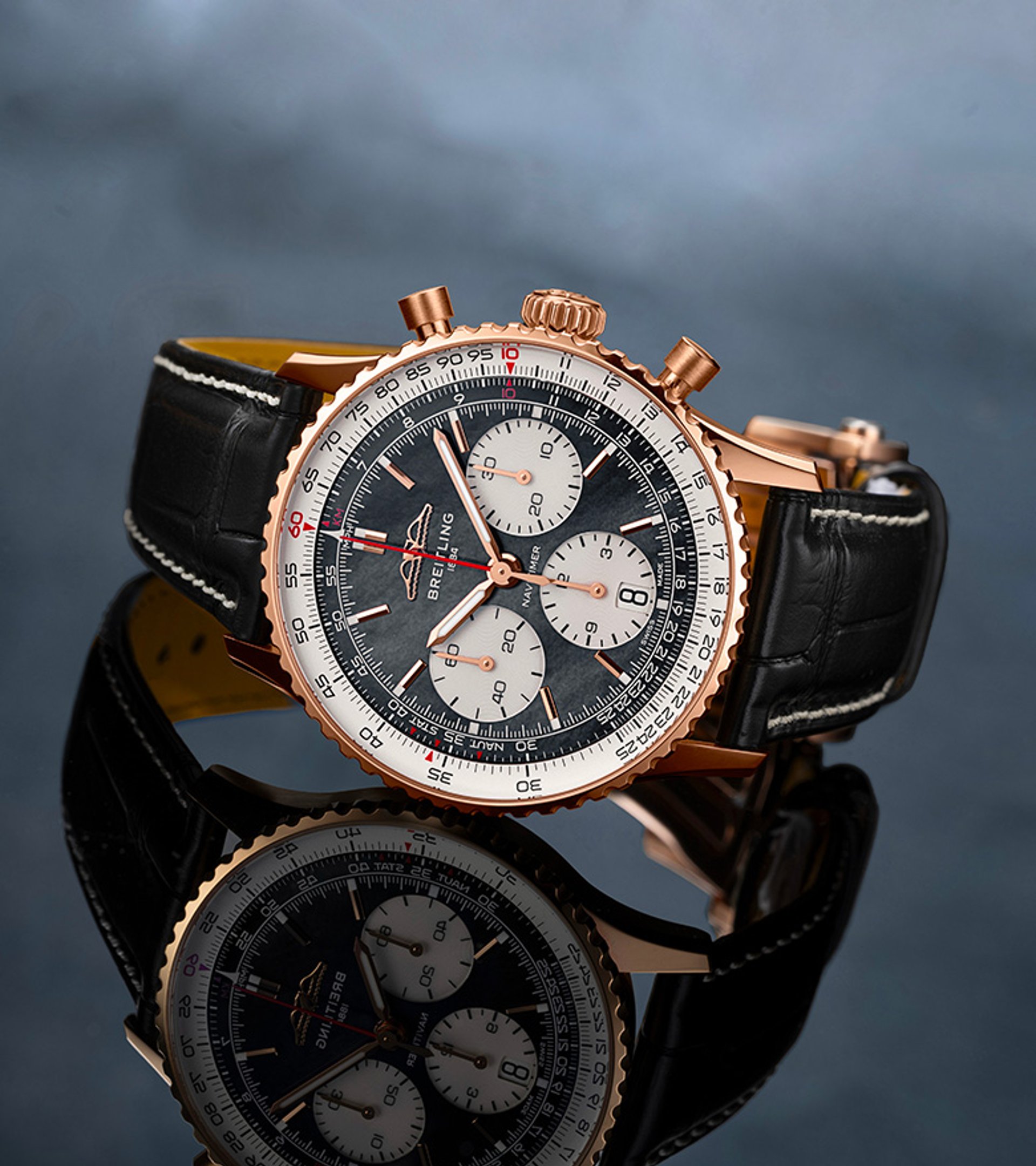 {generated} ブレイトリングのナビタイマーが黒いレザーストラップとともに暗い反射面に置かれ、細部が際立つ構図