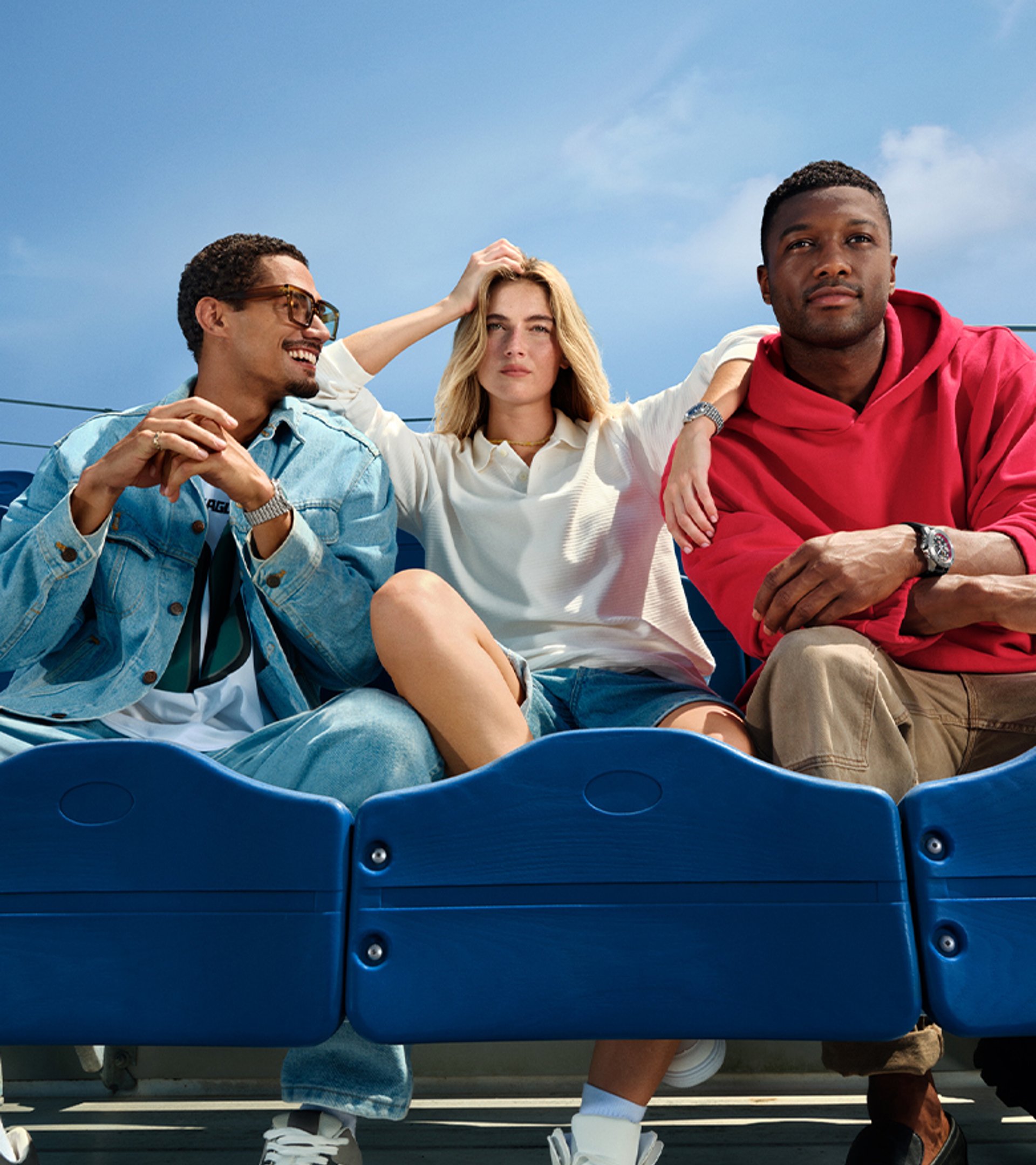 {generated} Three friends relax in bright blue stadium seats, each showcasing a Breitling watch in a casual NFL-inspired setting.