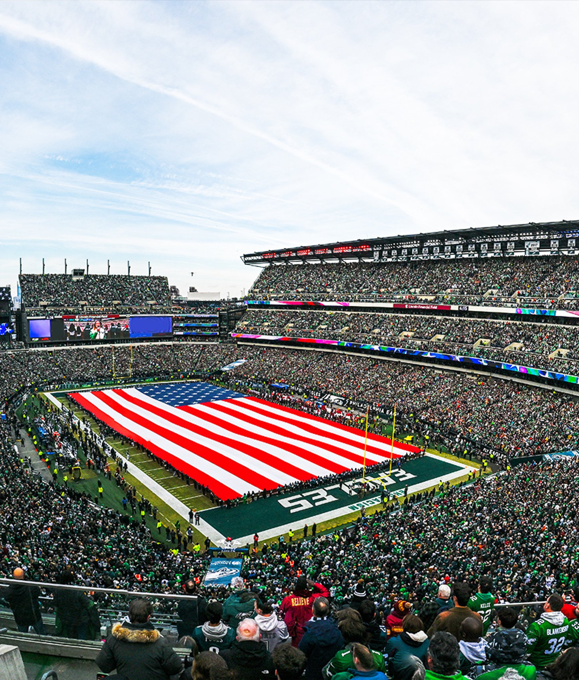 {generated} A packed NFL stadium displays a giant US flag across the field as fans gather for a high‑energy game day moment.