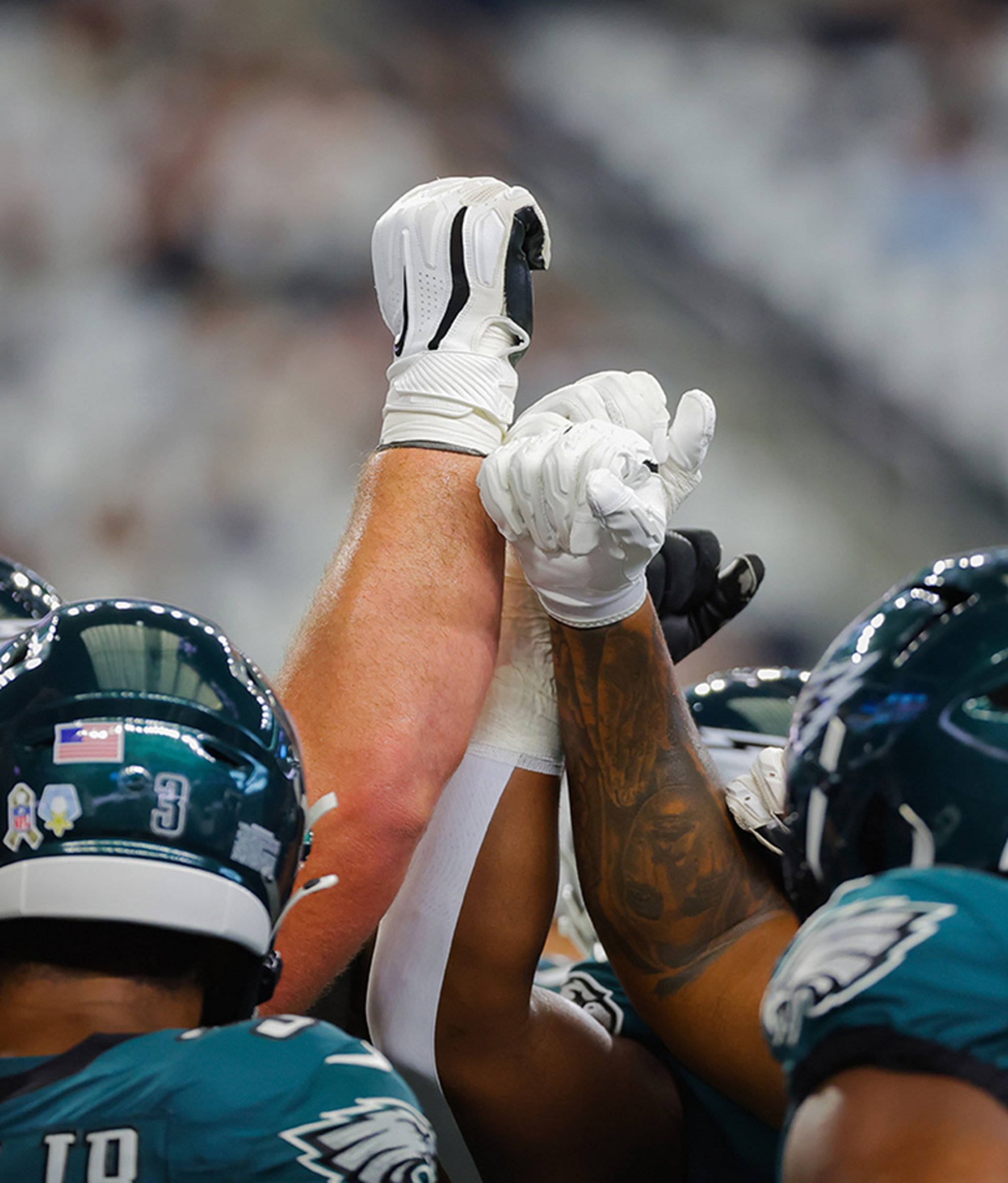 {generated} NFL players in green helmets raise gloved hands together in a tight huddle, capturing team unity and game‑day energy.