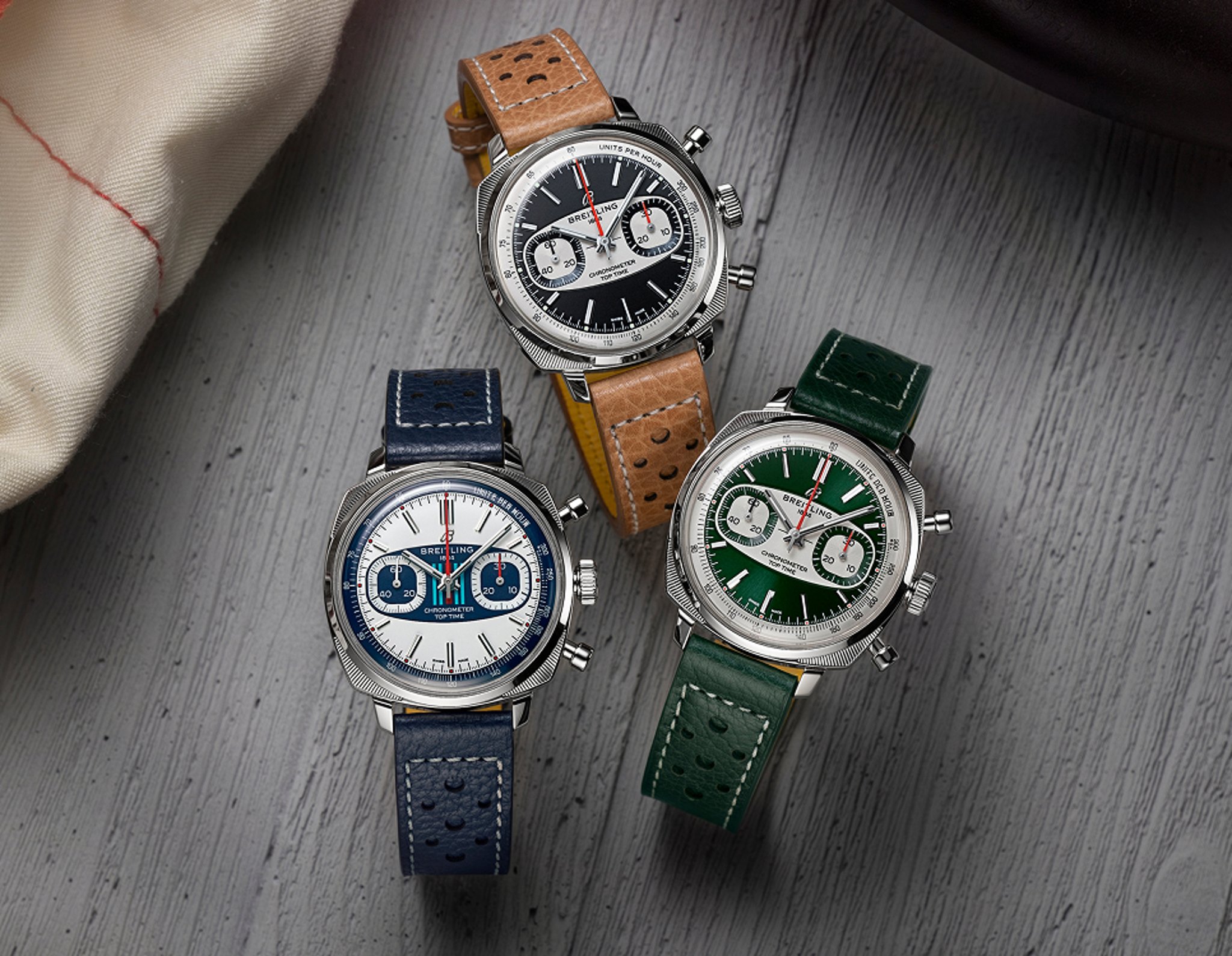 {generated} 三款Breitling Top Time計時腕錶以黑、白、綠錶盤搭配皮錶帶整齊陳列於灰色表面上