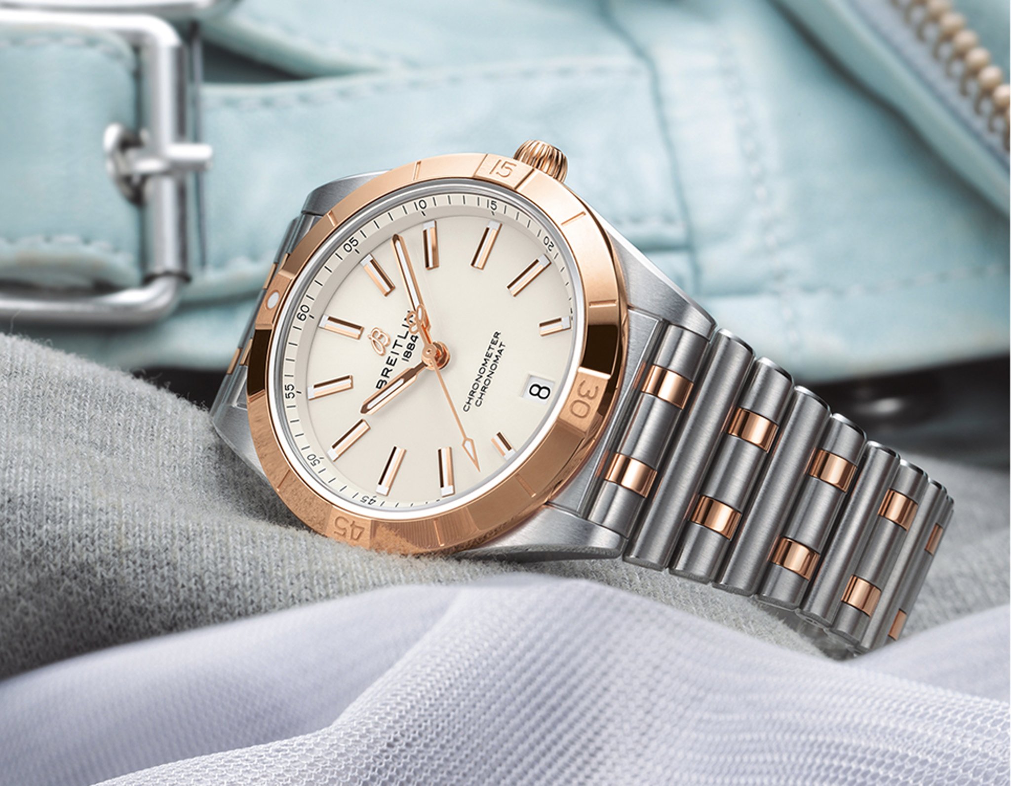 {generated} Breitling Chronomat doté d’un boîtier et d’un bracelet bicolores acier et or rose posé sur des textiles superposés