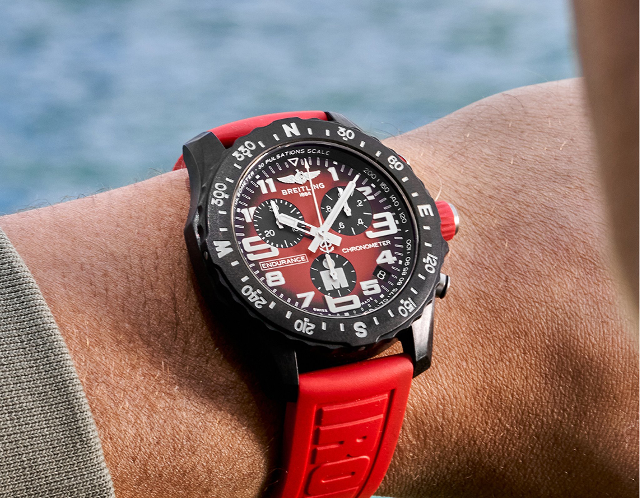 {generated} 佩戴紅色錶盤與錶帶的Breitling Endurance Pro於戶外呈現,突顯其鮮明的專業設計。