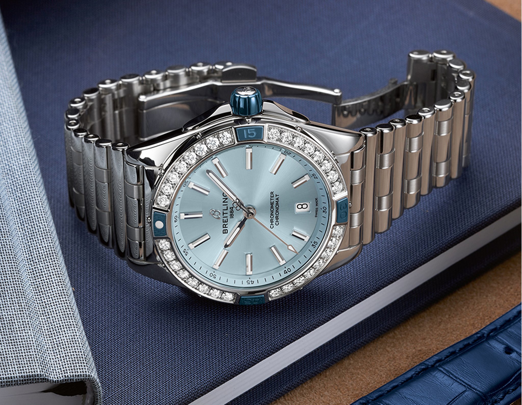 {generated} Breitling Chronomat doté d’un cadran bleu clair et d’une lunette diamantée posé sur des carnets dans un cadre de bureau raffiné