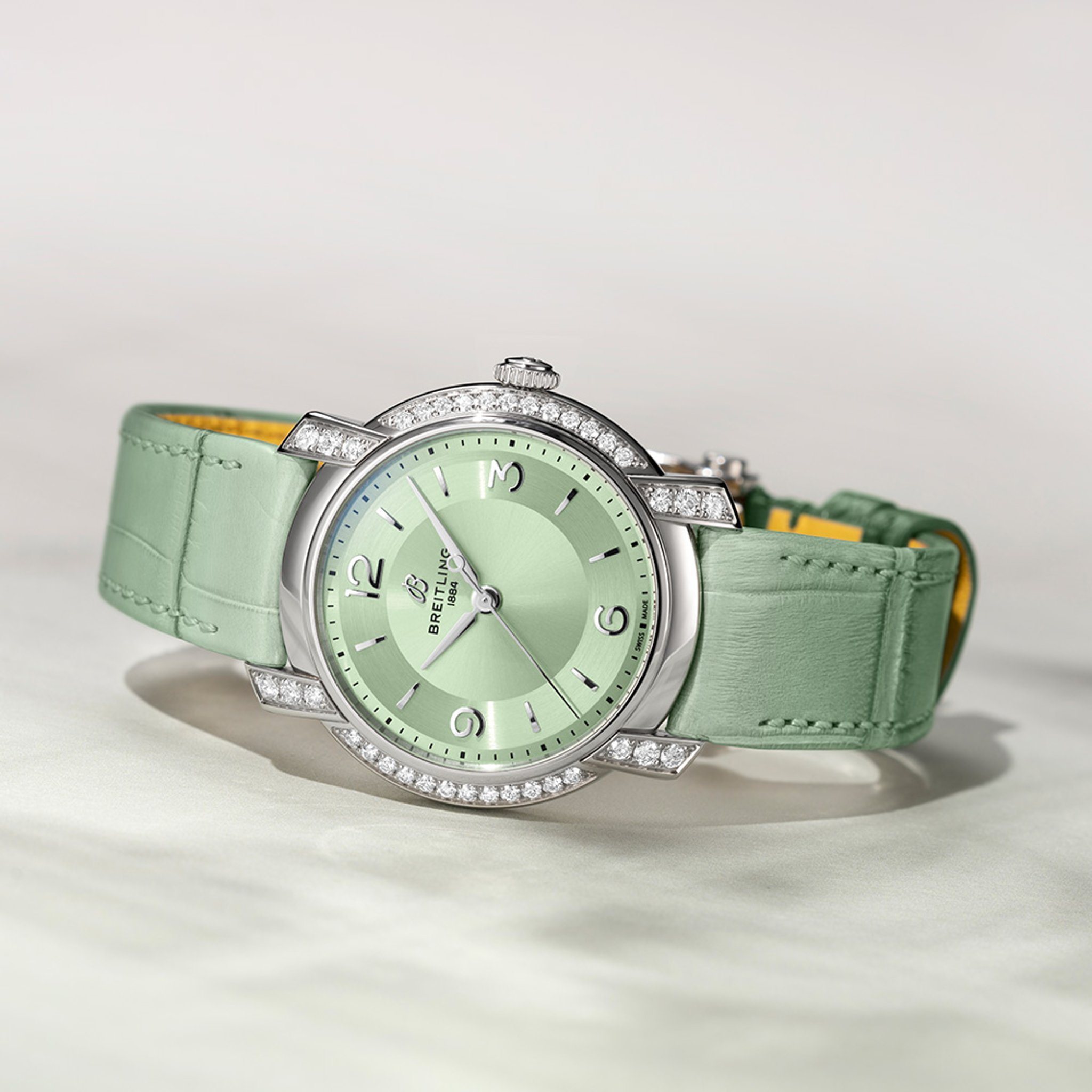 {generated} Breitling Lady Premier A10310671L1P1 con esfera verde, detalles de diamantes y correa a juego colocada sobre una superficie clara