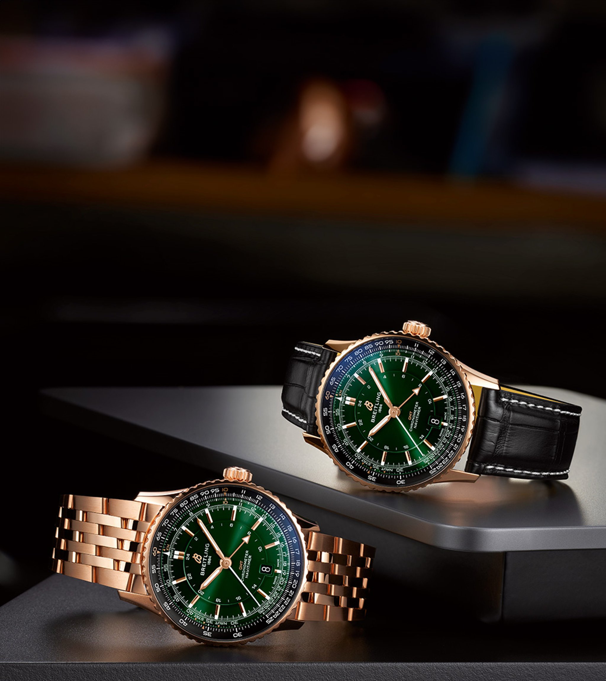 {generated} Two gold Breitling Navitimer watches with green dials, one on a bracelet and one on leather, set against a dark surface.