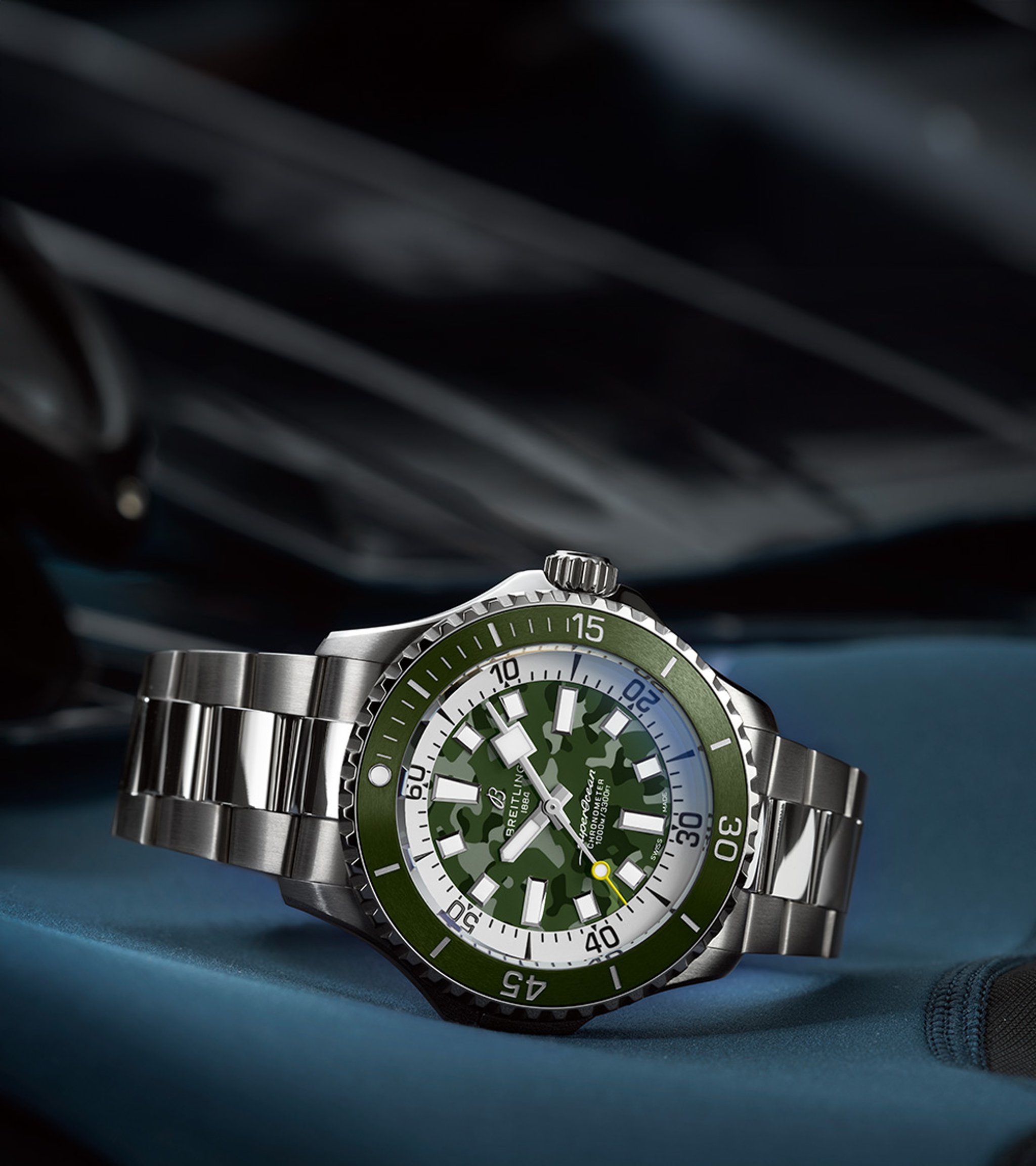 {generated} Breitling titanium watch featuring a green camo dial and steel bracelet set against dark gear to emphasise rugged precision.