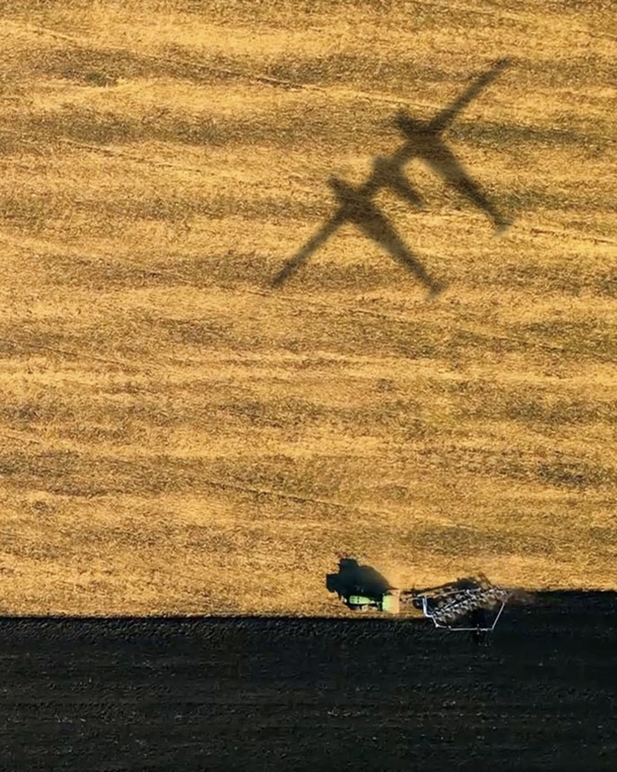 {generated} L’ombre d’un avion traverse des champs dorés tandis qu’un tracteur laboure la terre sombre, évoquant la vision de Climate Impulse