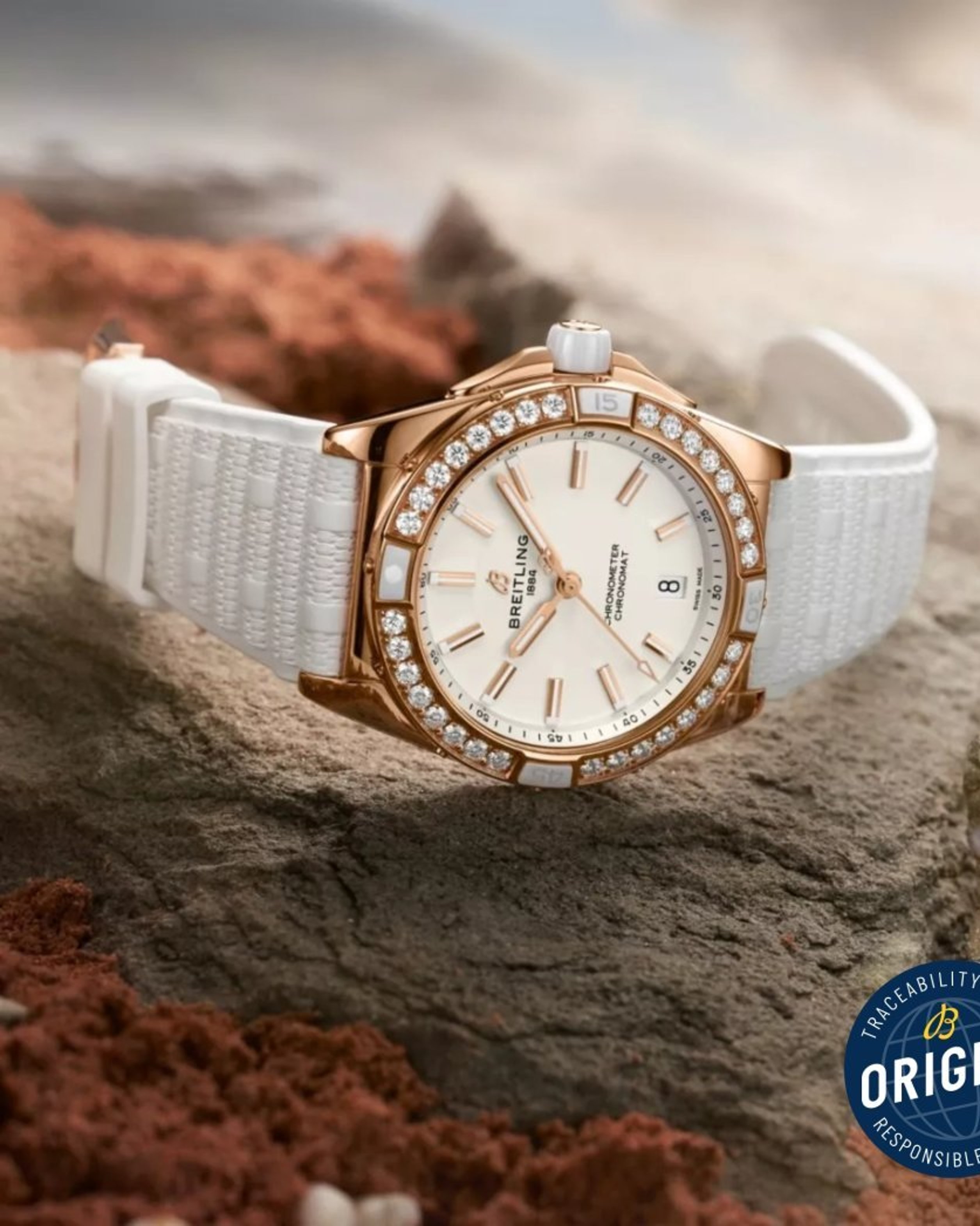 {generated} Montre Breitling Chronomat Origins en or rose avec lunette diamantée et bracelet blanc posée sur roches évoquant la traçabilité