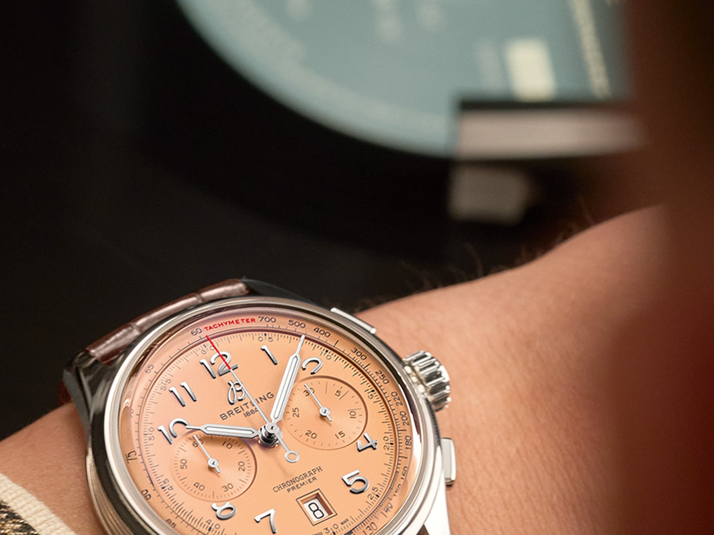 {generated} Cronógrafo Breitling con esfera salmón y correa de cuero marrón en la muñeca, resaltando sus detalles refinados
