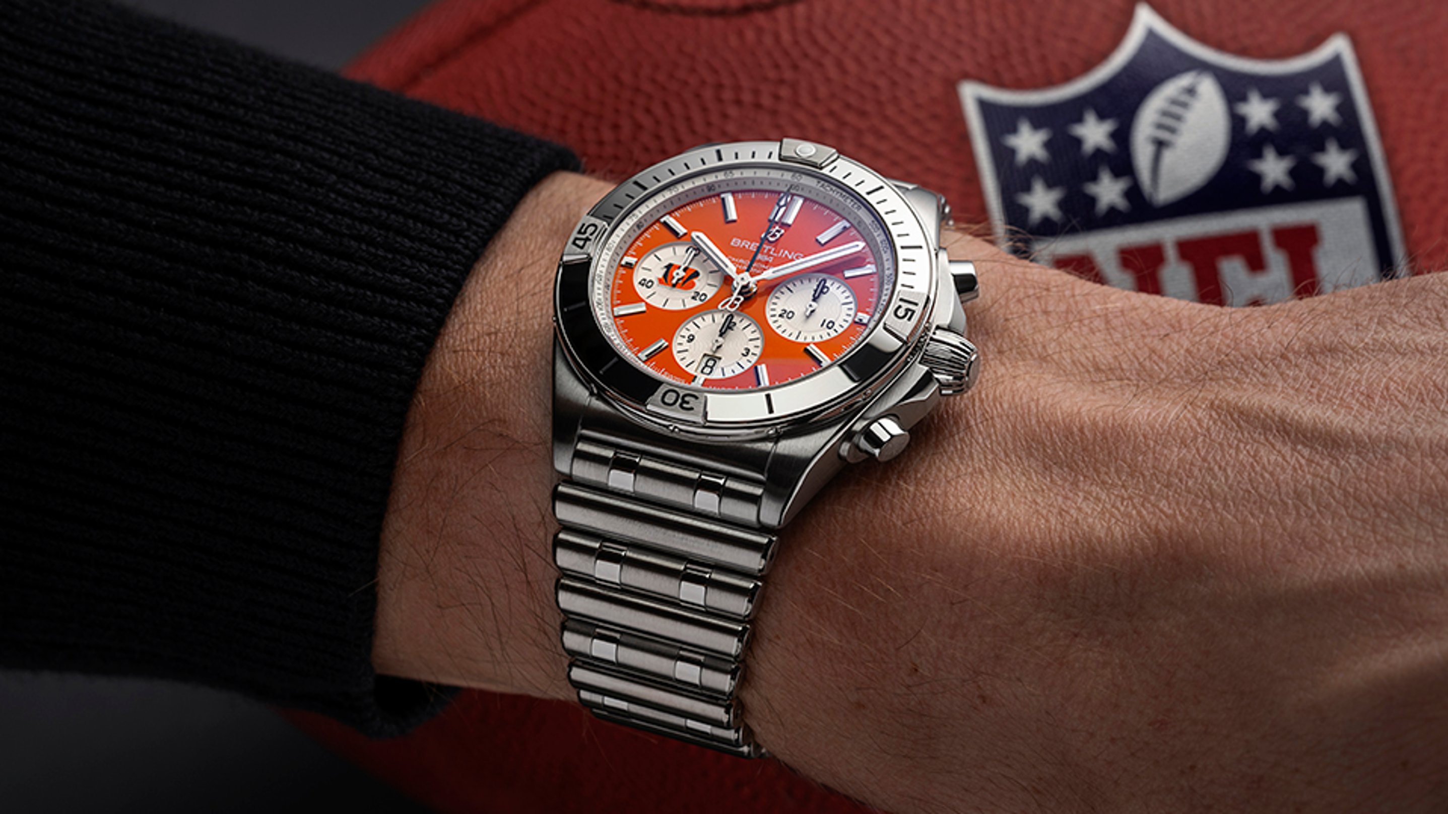 {generated} Breitling Chronomat with orange Cincinnati Bengals dial on a steel bracelet beside an NFL football to highlight team style